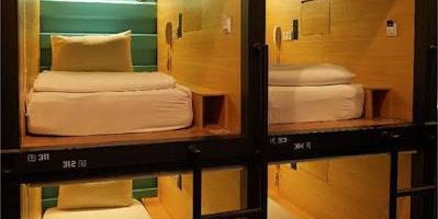Stacked sleeping capsules with wooden interiors, numbered frames and ladders to the upper pods.