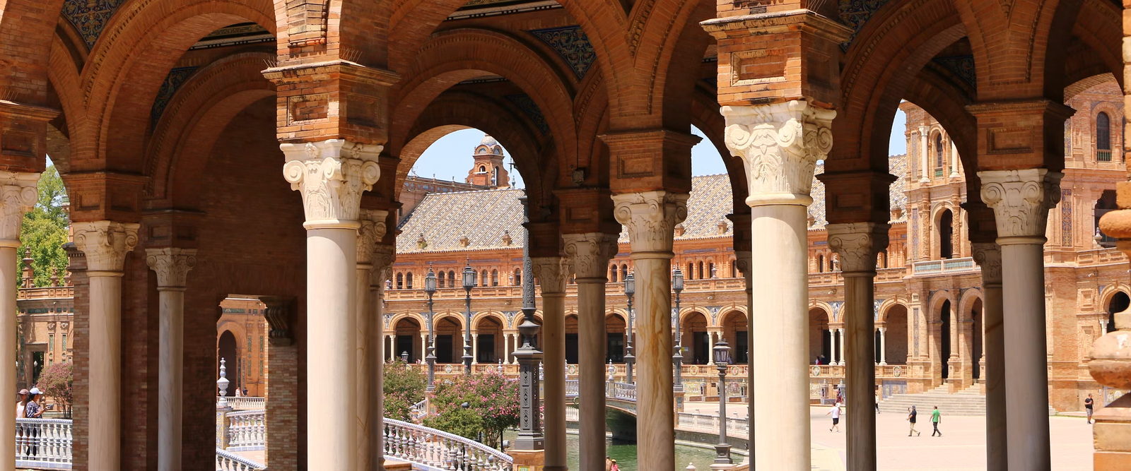 A brick arcade with tiled arches opening onto a wide public plaza.