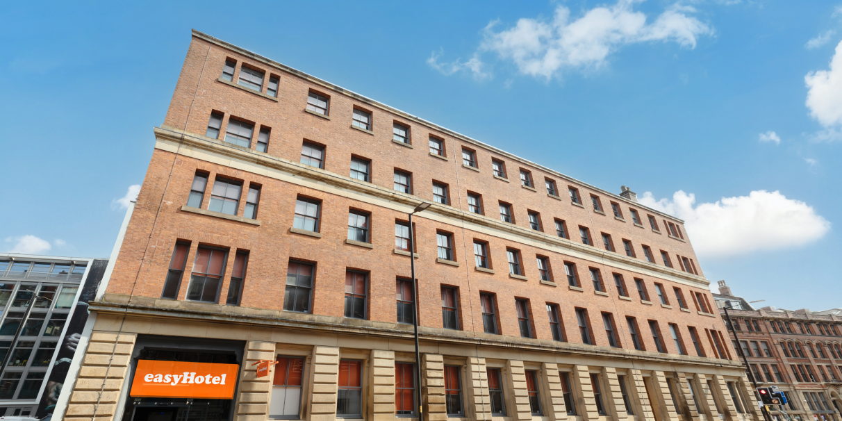 The brick street front of easyHotel Manchester, with the orange sign above the entrance.