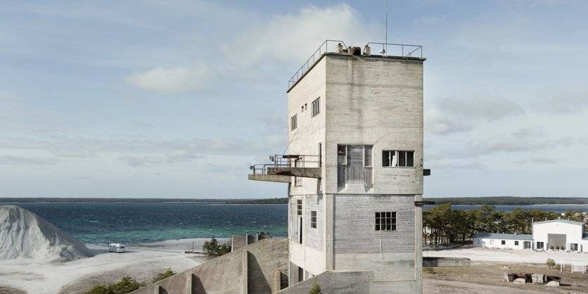A tall concrete tower standing on open ground near the water.