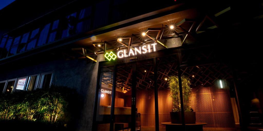 The lit glass entrance of Glansit at night, with the hotel name above the doors.